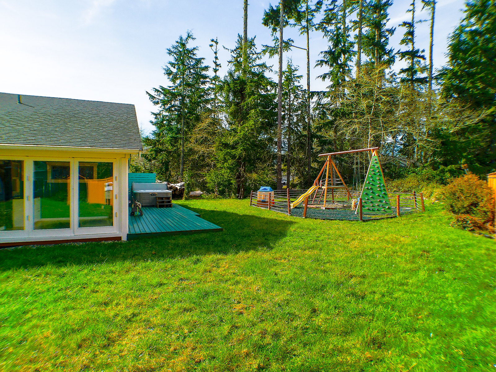 The large private backyard features an ample back deck, kids' playground, and a relaxing hot tub.