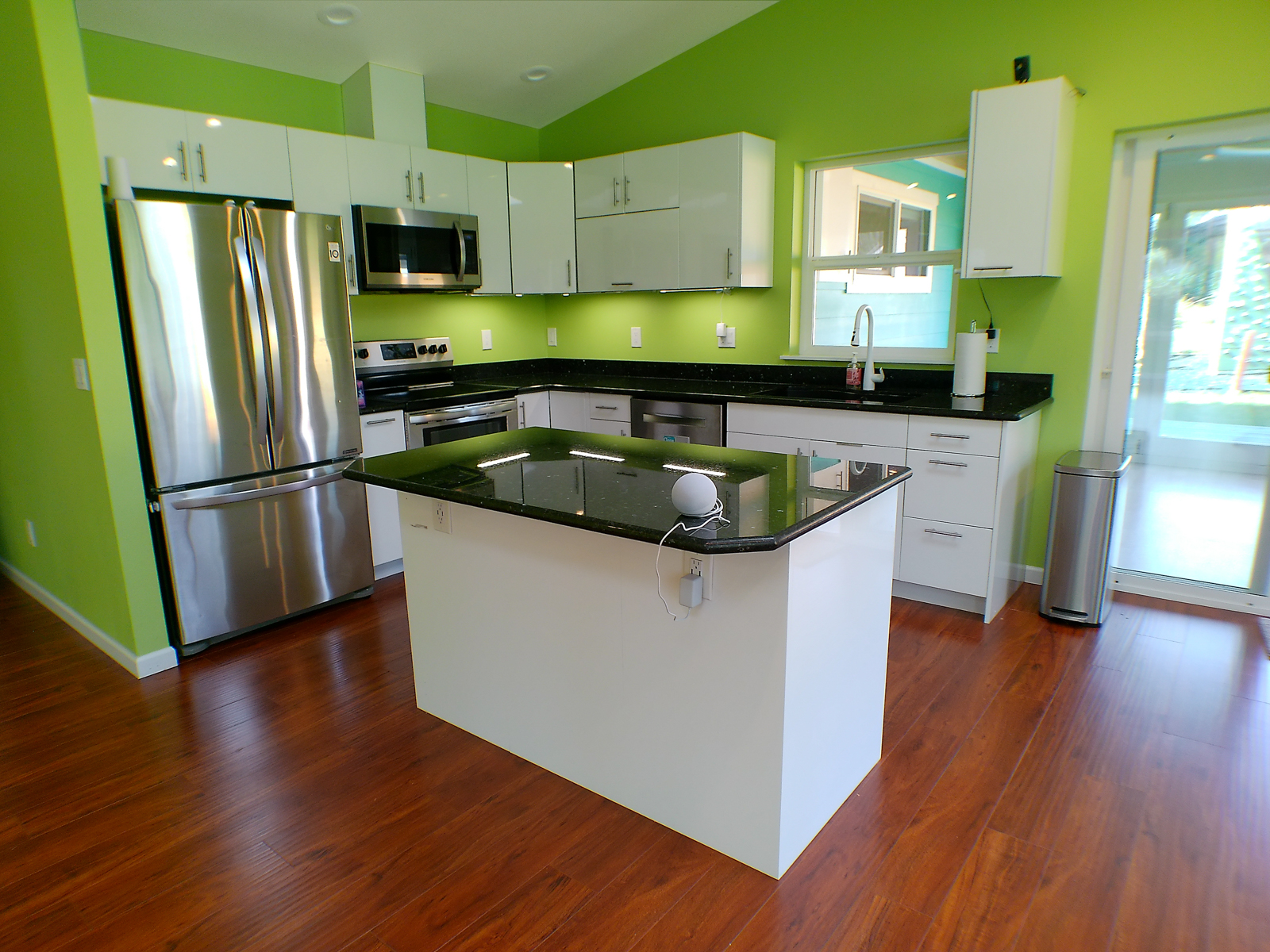 Stainless steel appliances and modern black granite countertops give the kitchen a sleek, contemporary feel. Generous cabinetry and a large island provide ample storage with a glossy, easy-to-clean surface. Appliances include a top-of-the-line LG refrigerator, Samsung oven and microwave with an externally venting range hood, and the highly rated Bosch dishwasher. The composite granite black kitchen sink is matched to the countertops for a cohesive finish.