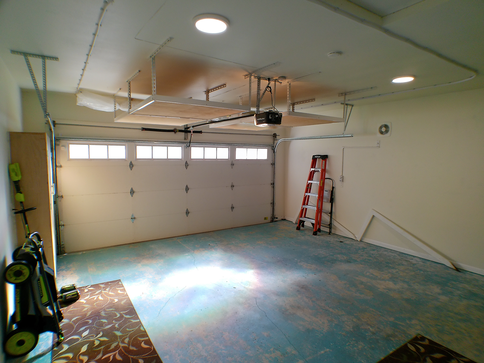 Inside, the garage features an EV charger, sturdy metal shelving, ceiling storage for boxes, and wall storage for garden tools.